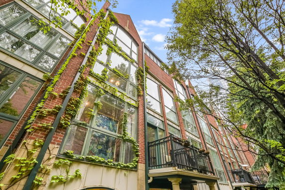 Front view of a multi-story brick building with large windows and ivy growing on the facade.