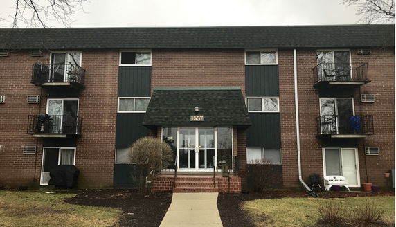 Front view of a multi-story brick apartment building with balconies.