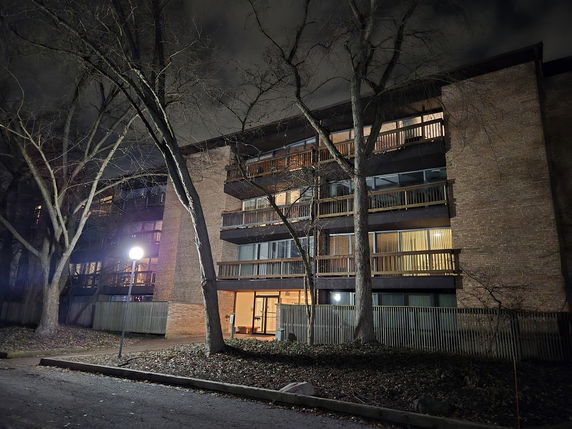 Front view of a multi-story apartment building with balconies at night.