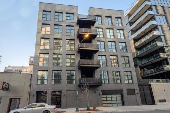 Front view of a modern multi-story apartment building with balconies.