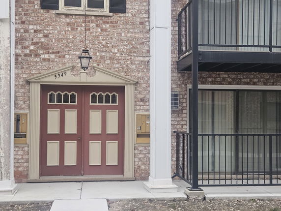 Front view of a brick building with a double door entrance and a balcony.