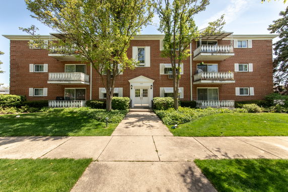 Front view of a three-story brick apartment building with balconies.