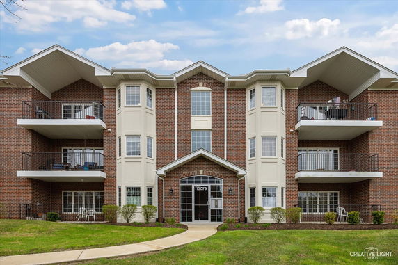 Front view of a multi-story brick building with balconies and large windows.