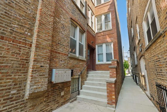 Front view of a multi-story brick building with steps leading to the entrance.