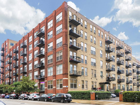 Front view of a multi-story apartment building with balconies and brick facade.
