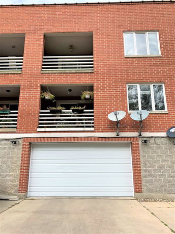 Front view of a brick building with balconies and a garage door.