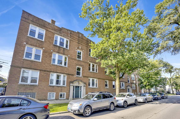 Front view of a multi-story brick apartment building with multiple windows.
