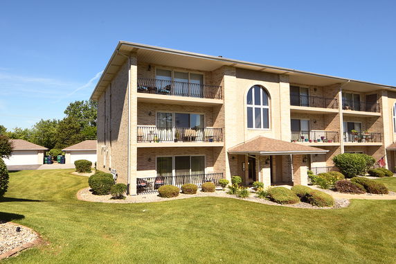 Front view of a multi-story brick apartment building with balconies.