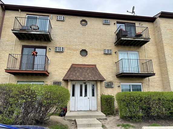 Front view of a three-story apartment building with balconies and a central entrance.