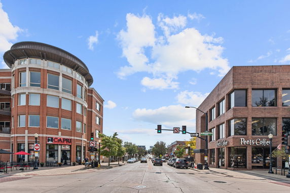 Street view with a round cornered multi-level building and a rectangular brick building.