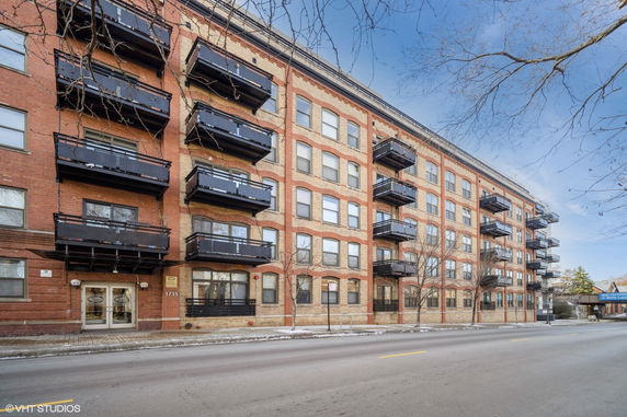 Front view of a multi-story apartment building with brick facade and balconies.