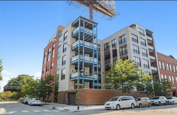 Front view of a multi-story building with balconies and brick facade.