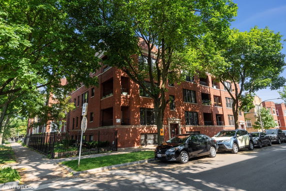 Front view of a multi-story brick apartment building with several balconies.