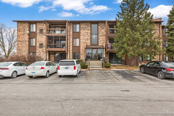 Front view of a three-story brick apartment building with balconies.