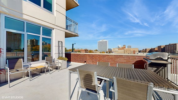 Rooftop with seating and a grill overlooking the city skyline.