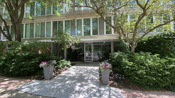 Front view of a modern building with large windows and a path leading to the entrance.
