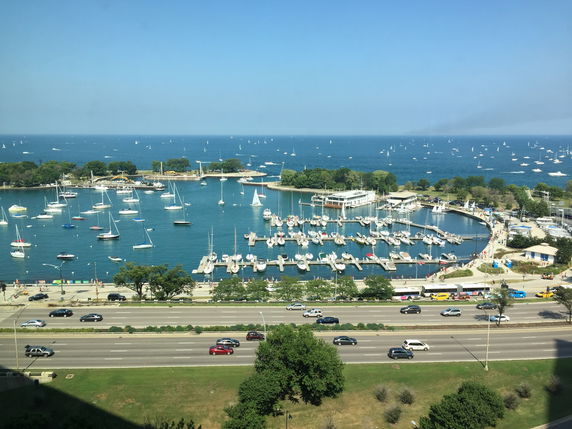 Panoramic view of a marina with numerous sailboats and a distant view of the ocean.
