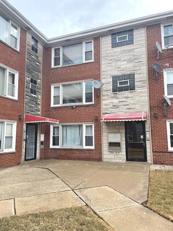 Front view of a three-story brick apartment building with red awnings.