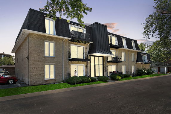 Front view of a multi-story building with balconies and a distinctive roof design.