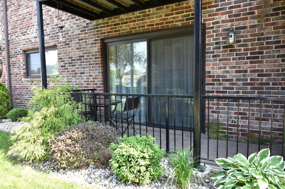 Brick building facade with a patio area featuring sliding glass doors and a small seating arrangement.