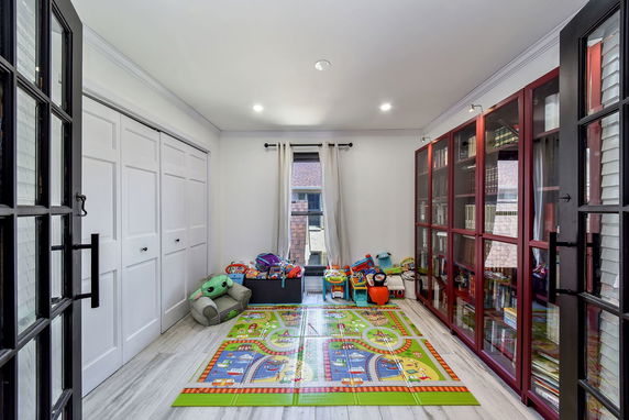 Room with children's play mat and toys, glass cabinet, and window.