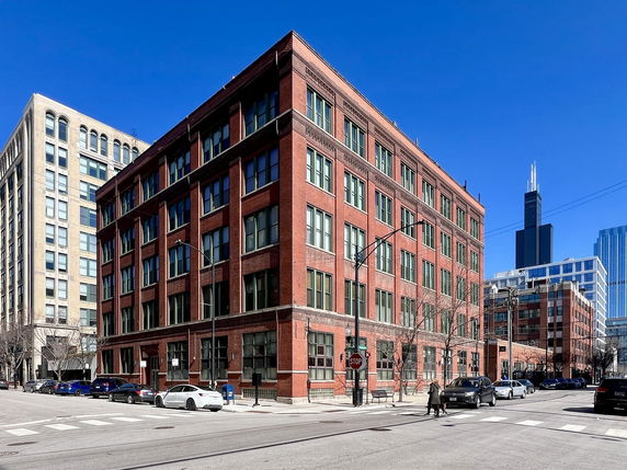 Front view of a red brick multi-story building on a city street.