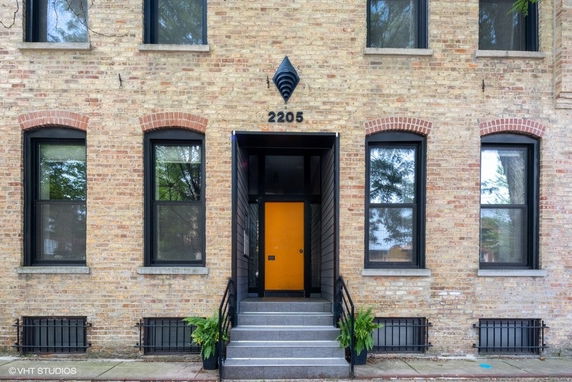 Front view of a brick building with a central entrance and arch-top windows.