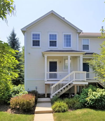 Front view of a two-story house with a small porch and staircase.