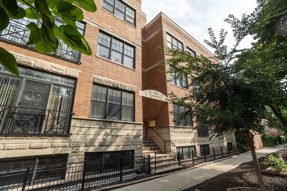 Front view of a multi-story brick building with large windows and a small entry staircase.