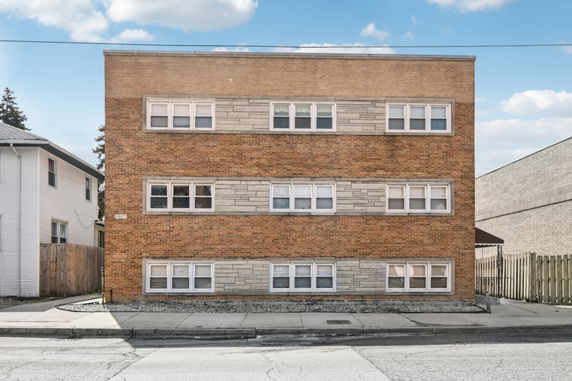 Front view of a three-story brick building with multiple windows.