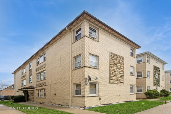 Front view of a multi-story brick apartment building with stone accents.