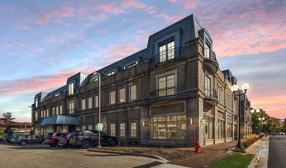 Front view of a multi-story building with modern architectural design and parking area.