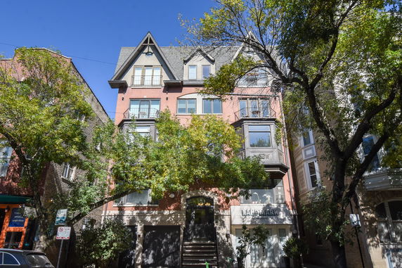 Front view of a multi-story brick apartment building with multiple gabled roofs and balconies.