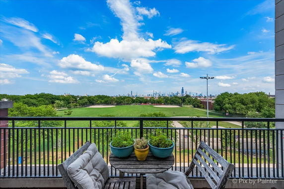 View from a balcony overlooking a park with a city skyline in the distance.