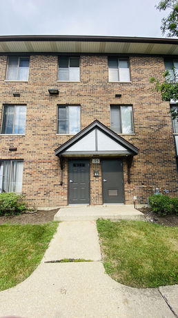 Front view of a multi-story brick apartment building entryway.