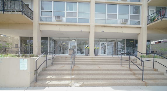 Front view of a modern apartment building with multiple balconies and entrance steps.
