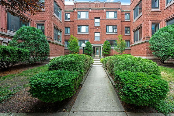 Front view of a brick apartment building with multiple windows.