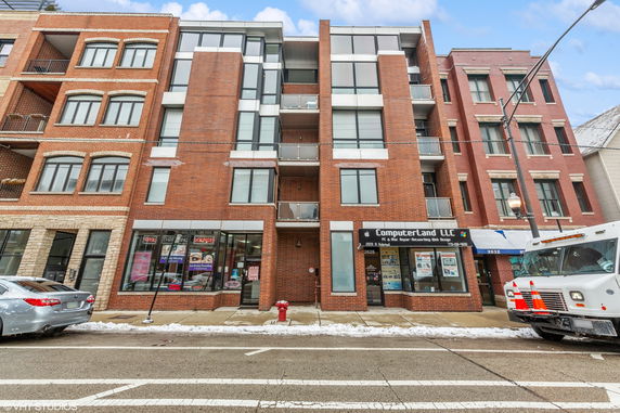 Front view of a multi-story building with brick exterior and ground floor shops.