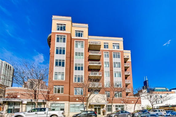 Front view of a multi-story brick apartment building with balconies and large windows.