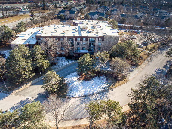 Aerial view of a multi-story building with a flat rooftop and surrounding roads.