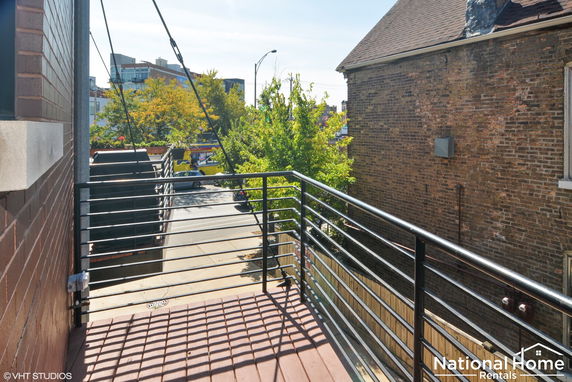 View from a second-story balcony overlooking a street and nearby buildings.