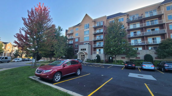 Front view of a multi-story residential building with a parking lot.