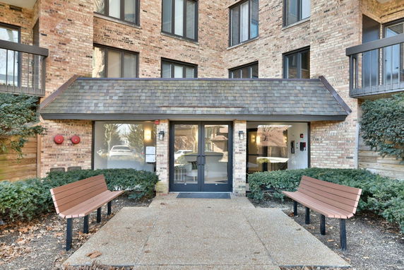 Front view of a multi-story brick building with large windows and an entrance canopy.