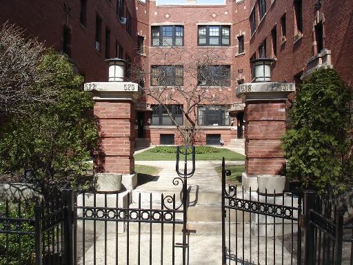Front view of a multi-story brick building with a gated entrance.