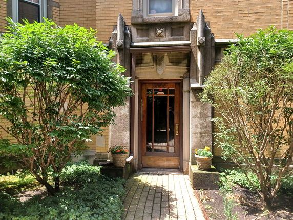 Entrance view of a building with brick walls and a wooden door with decorative stonework.