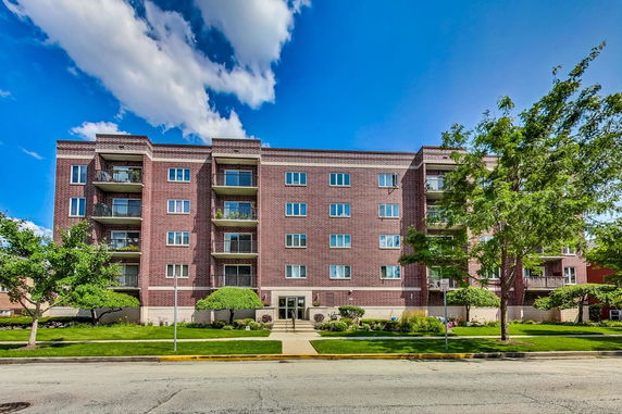 Front view of a multi-story brick apartment building with balconies.