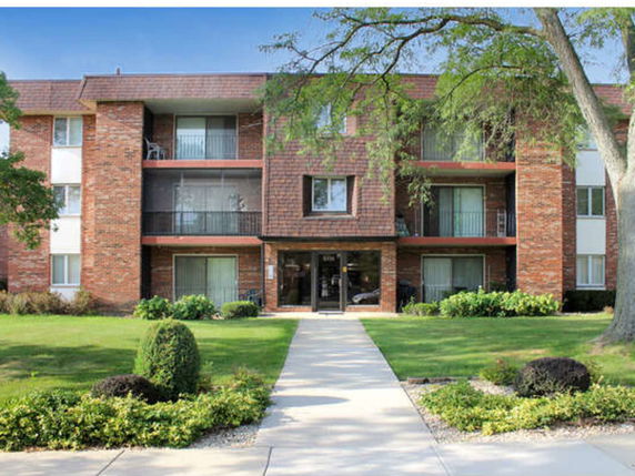Front view of a three-story brick apartment building with balconies.