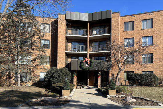 Front view of a multi-story apartment building with balconies and festive decorations.