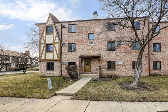 Front view of a three-story brick apartment building with a decorative façade.