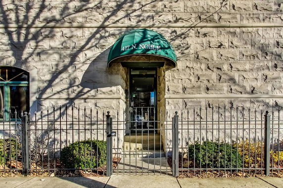 Front view of a building with a stone exterior and a green awning above the entrance.